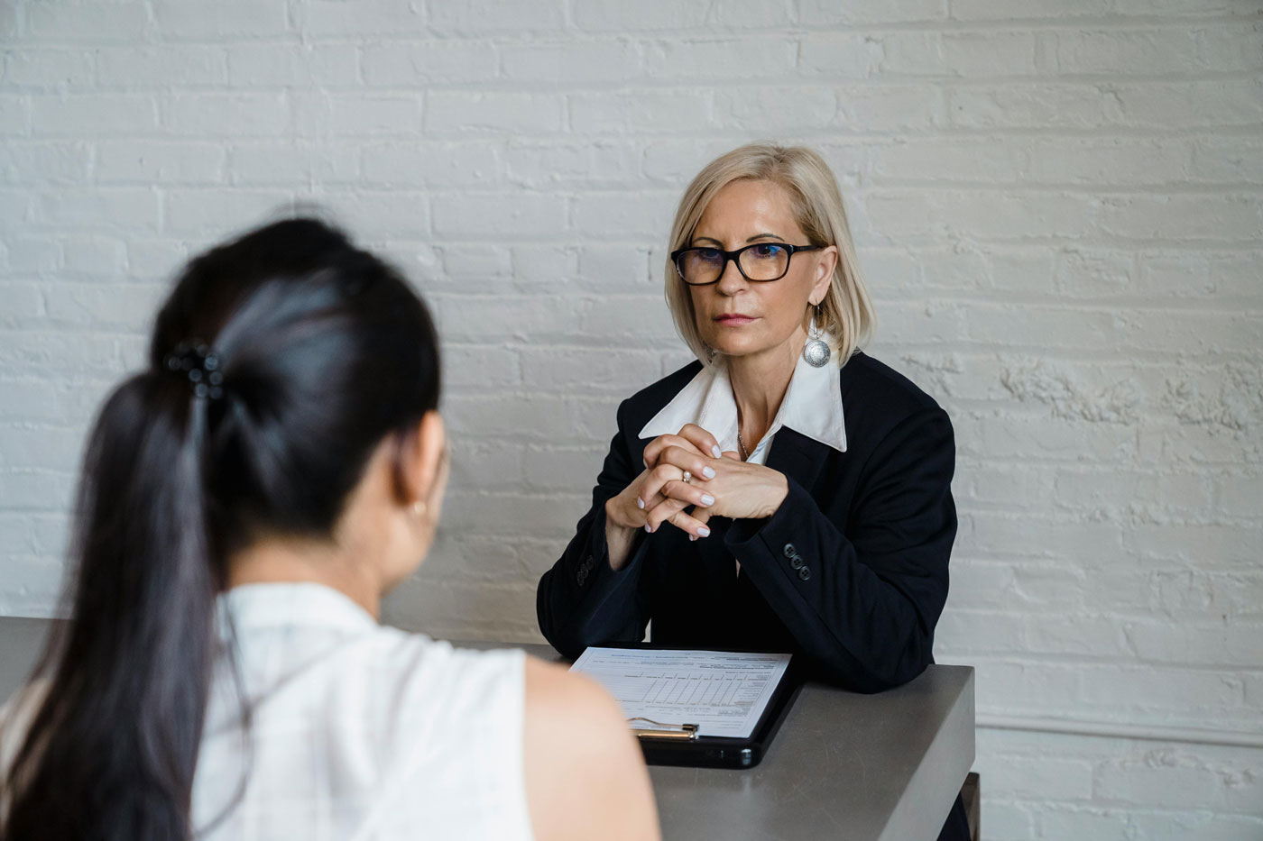 Recruiter interviewing candidate across a desk, highlighting thorough vetting in staff hiring